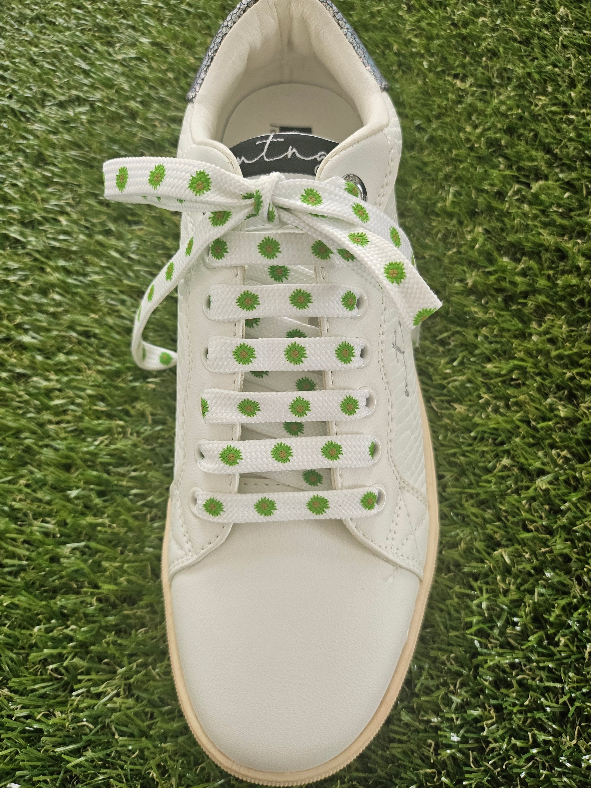 White sneaker with green polka dot laces on grass